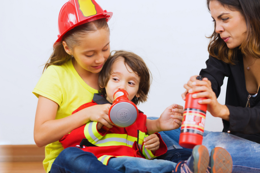 Parent and children learning about fire safety with a toy fire extinguisher