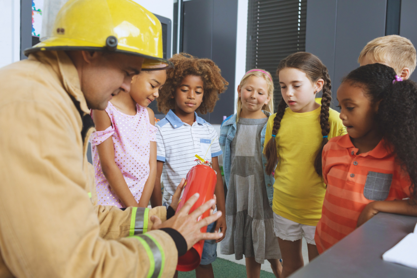 Firefighter teaching a group of preschool children about fire safety