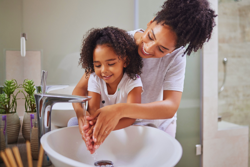 Mother and child washing hands practicing good hygiene at home