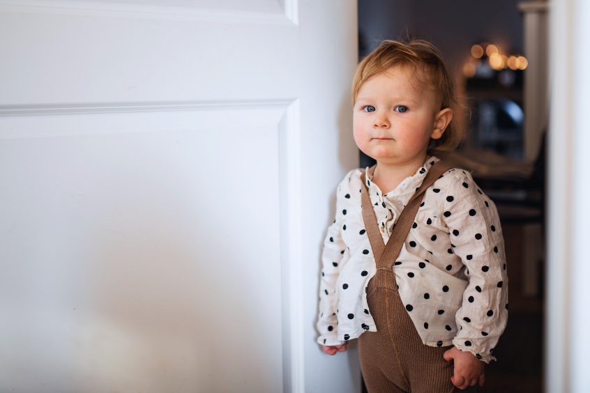 Young child standing in a doorway at night after getting out of bed